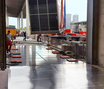 Lowering a machine onto air cushions using a crane along a perfectly prepared access route lined with stainless steel plates